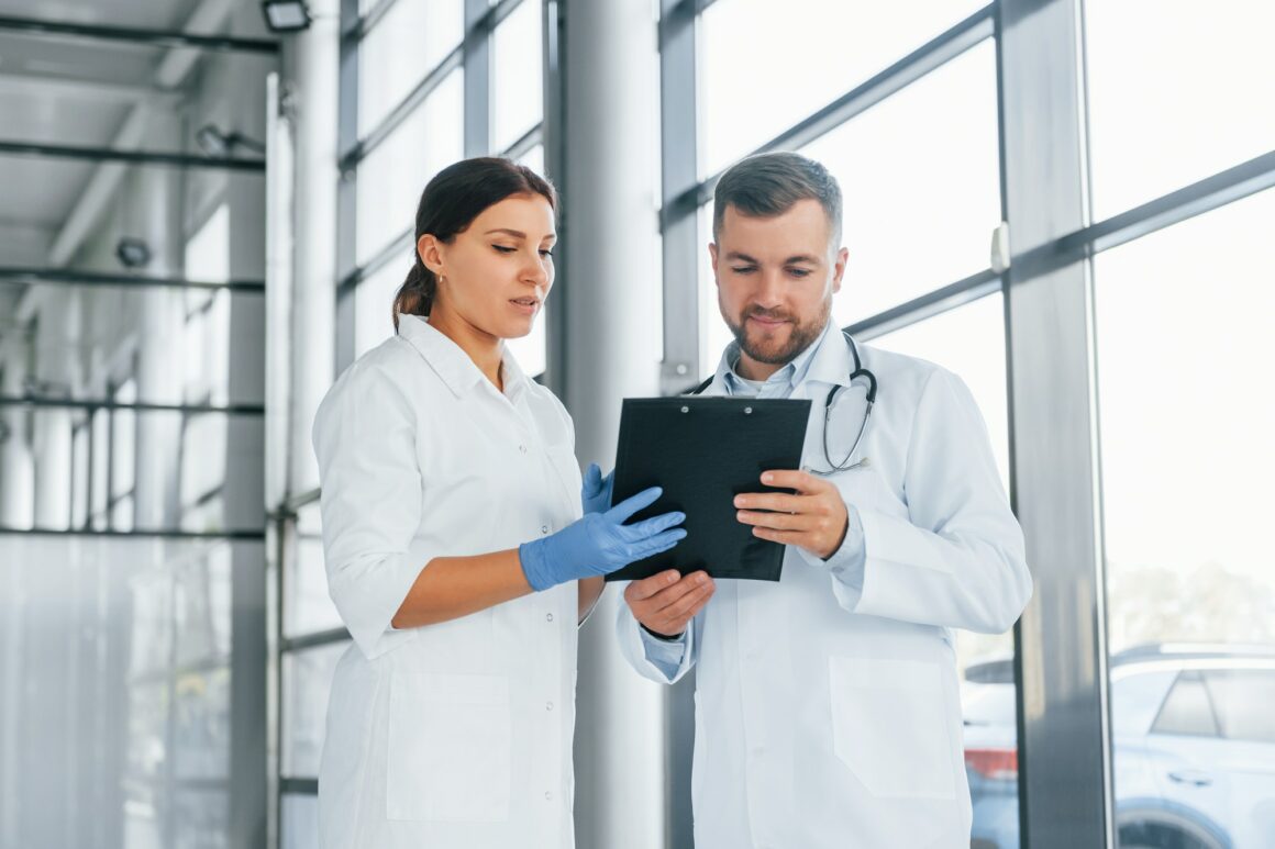 Busy people. Two doctors in white coats is in the clinic working together