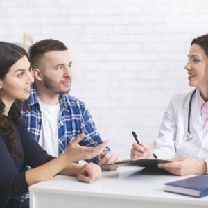 Cheerful doctor talking with millennial family about health care Cheerful doctor talking with millennial family about health care