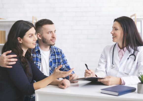Cheerful doctor talking with millennial family about health care