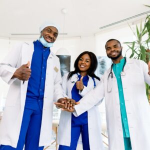 Doctors team. Health care. Three happy African doctors stack hands together as team for motivation