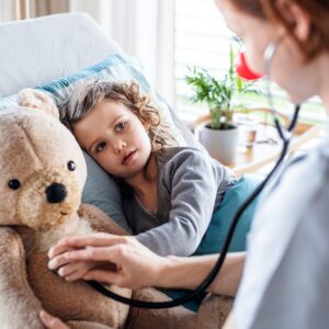 Friendly female doctor examining small girl in bed in hospital. Friendly female doctor examining small girl in bed in hospital.