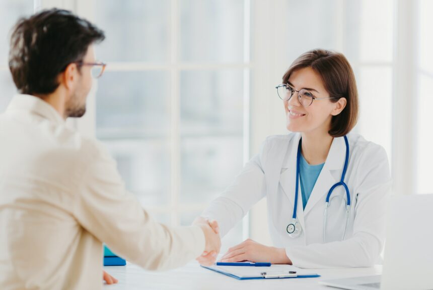 Friendly female doctor greets patient with handshake, pose in private clinic